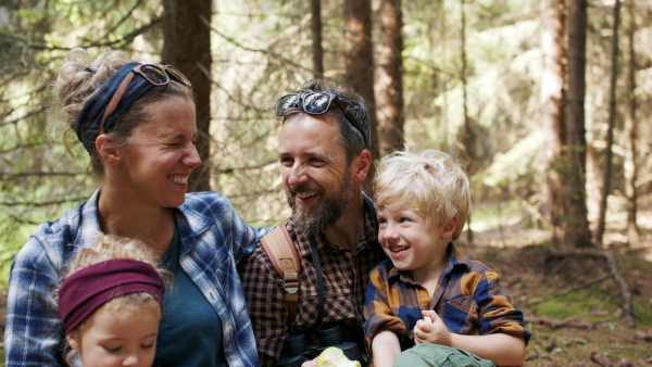 A family with small children having picnic in summer forest .