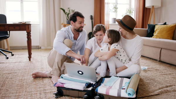 A beautiful family packing and making preparations for vacation on laptop.