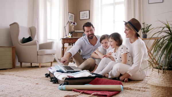 A beautiful family packing and making preparations for vacation on laptop.