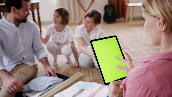 A beautiful family making preparations for vacation on tablet with green screen.