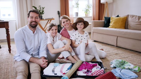 Beautiful family preparing for vacation, little daughter playing with sun lotion, looking at camera.