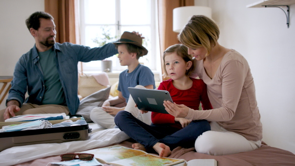 A beautiful family packing and making preparations for vacation on tablet.