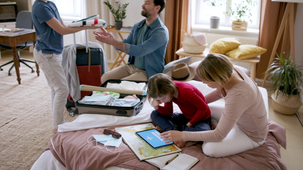 A beautiful family packing and making preparations for vacation on tablet.