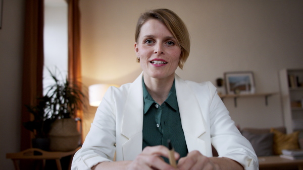 A front view of woman having an online call, looking at camera.