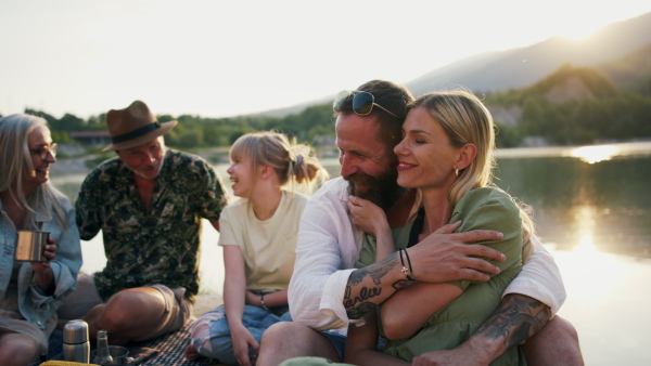 A happy multigeneration family on summer holiday trip, barbecue by lake.