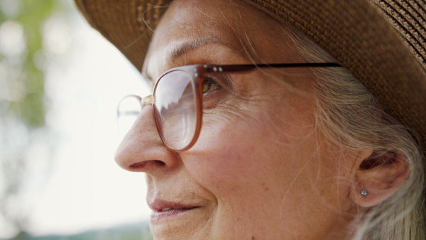 A close up of happy senior woman in sun hat on summer beach