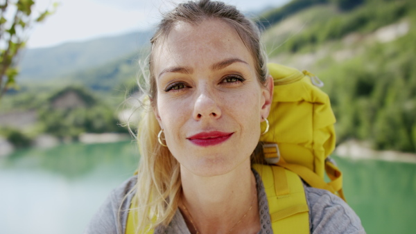 A close-up of happy mid adult woman tourist hiking in nature by lake.