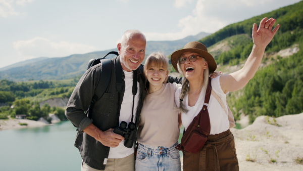 A happy preteen girl with grandparents on hiking trip on summer holiday, looking at camera.