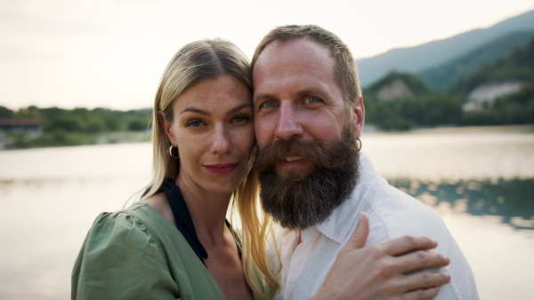 A happy mature couple in love hugging in nature, looking at camera.