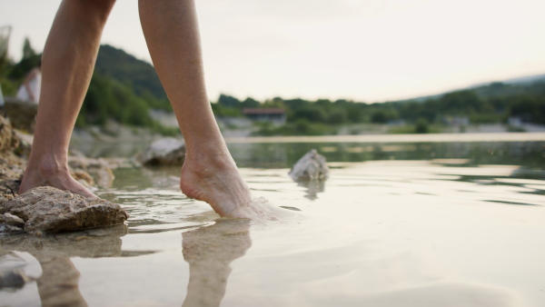 A low section of woman walking alone in lake in summer.