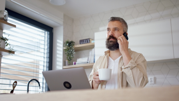 A hipster businessman at home office, having a call and coffee.