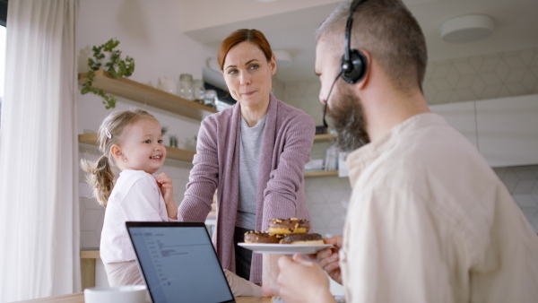 A beautiful family at home, father working, having breakfast and playing with daughter.