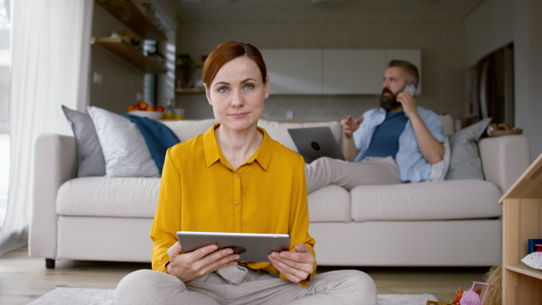 A happy family at home, parents working, mother looking at camera.