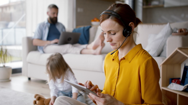 A happy family at home, parents working, mother looking at camera.