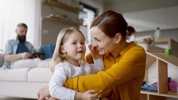 A happy family at home, father working, mother playing with daughter.