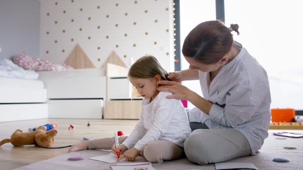 Busy mother preparing her daughter for kindergarten, making her hair.