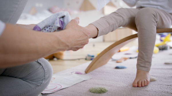 Busy mother preparing her daughter for kindergarten. Close up of foot and socks.