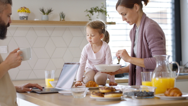 A beautiful family at home, mother with daughter having a breakfast, father working.