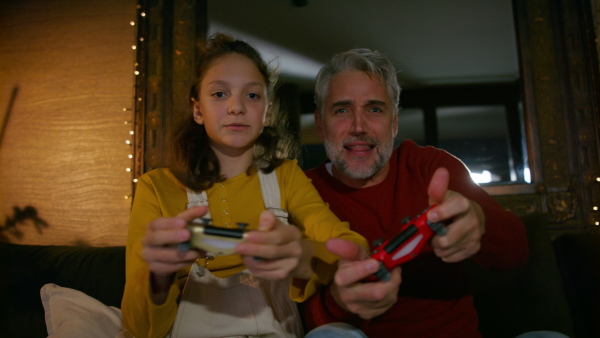 Father and daughter holding a game controller, playing video games. Enjoying family time together.