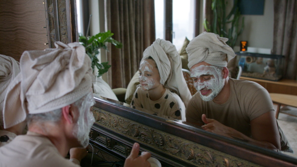 A teenage daughter applying face mask to her father at home