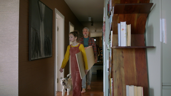 A father and teen daughter carrying flat-packed furniture to renovate their apartment.