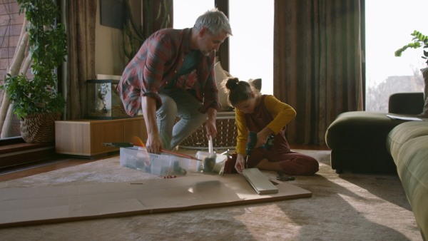 A father and teen daughter assembling new furniture in the renovated apartment