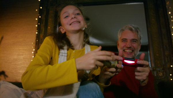 Father and daughter holding a game controller, playing video games. Enjoying family time together.