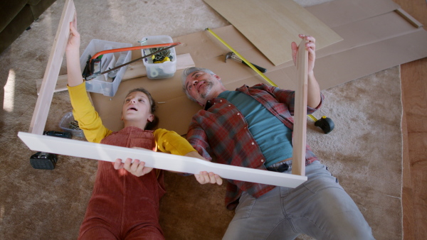 A father and teen daughter assembling new furniture in the renovated apartment