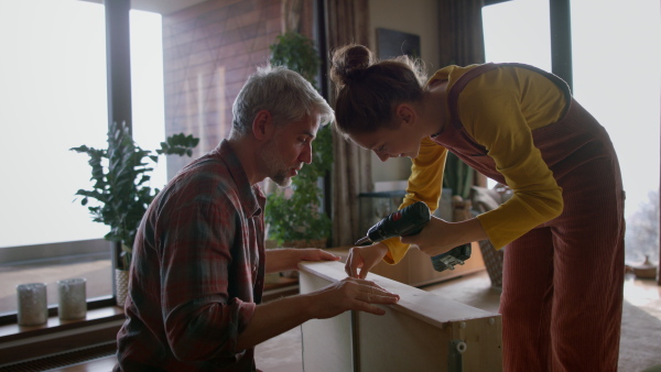 A father and teen daughter assembling new furniture in the renovated apartment