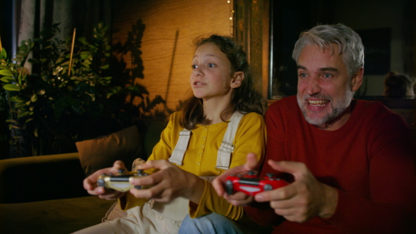 Father and daughter holding a game controller, playing video games. Enjoying family time together.