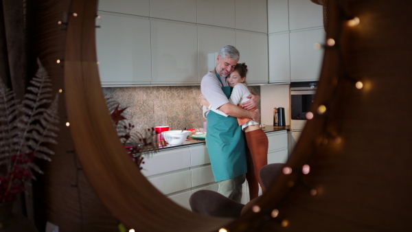 A teenage daughter with her father cooking in kitchen together.