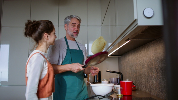 A teenage daughter with her father cooking in kitchen together.