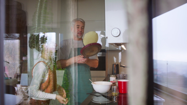 A teenage daughter with her father cooking in kitchen together.