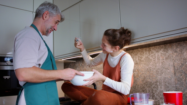 A teenage daughter with her father cooking in kitchen together.