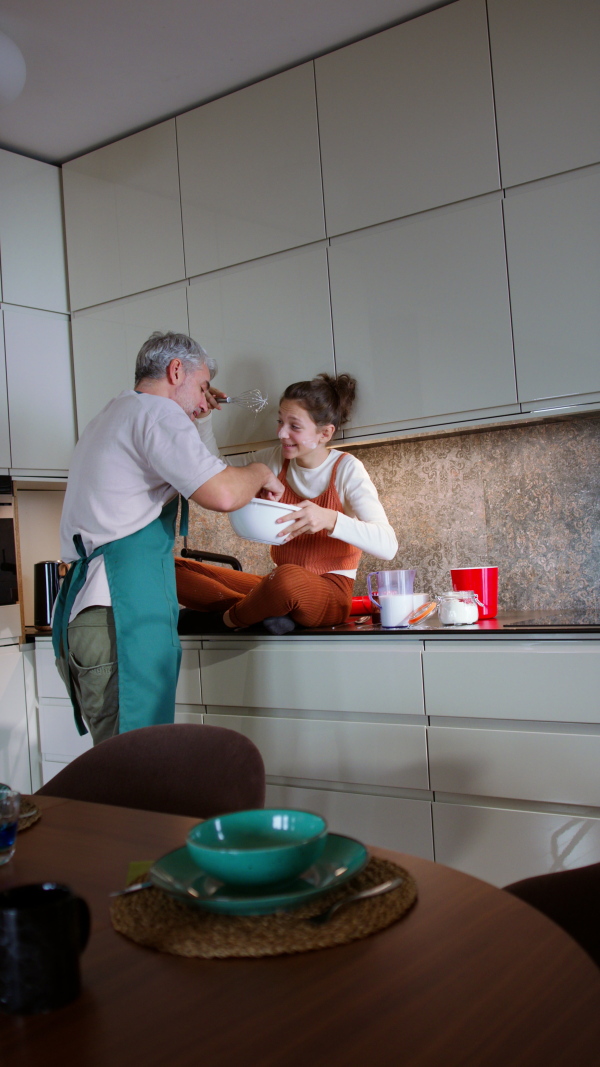 A vertical footage of eenage daughter with her father cooking in kitchen together.