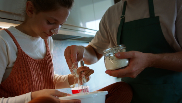 A teenage daughter with her father cooking in kitchen together.