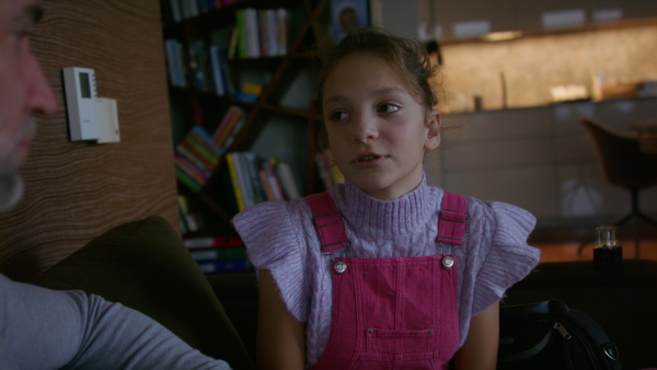 A sad teenage girl crying when talking to her father at home.