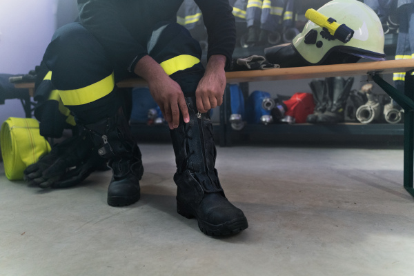 A lowsection of firefighter preparing for action in fire station at night