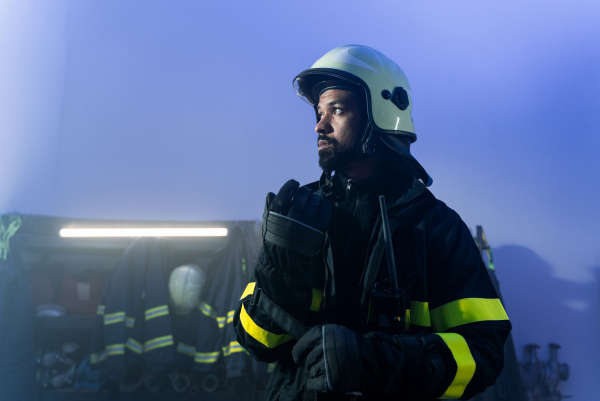 A young African-American firefighter in fire station at night.