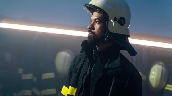 A young African-American firefighter in fire station at night.