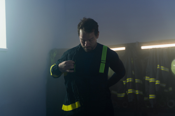 A young African-American firefighter in fire station at night.