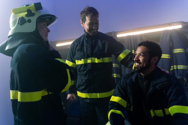 Happy firefighters men and woman talking after an action indoors in fire station