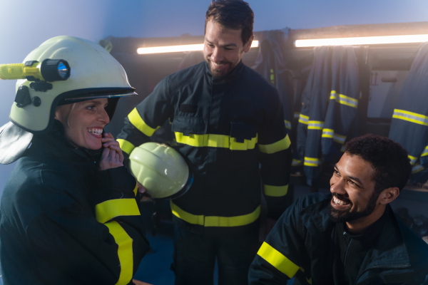 Happy firefighters men and woman talking after an action indoors in fire station