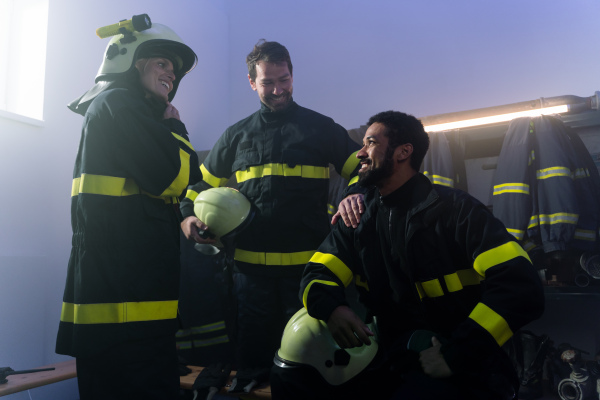 Happy firefighters men and woman talking after an action indoors in fire station