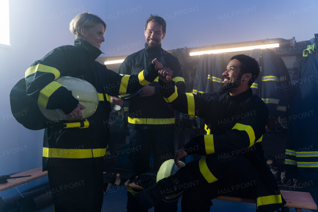 Happy firefighters men and woman talking after an action indoors in fire station