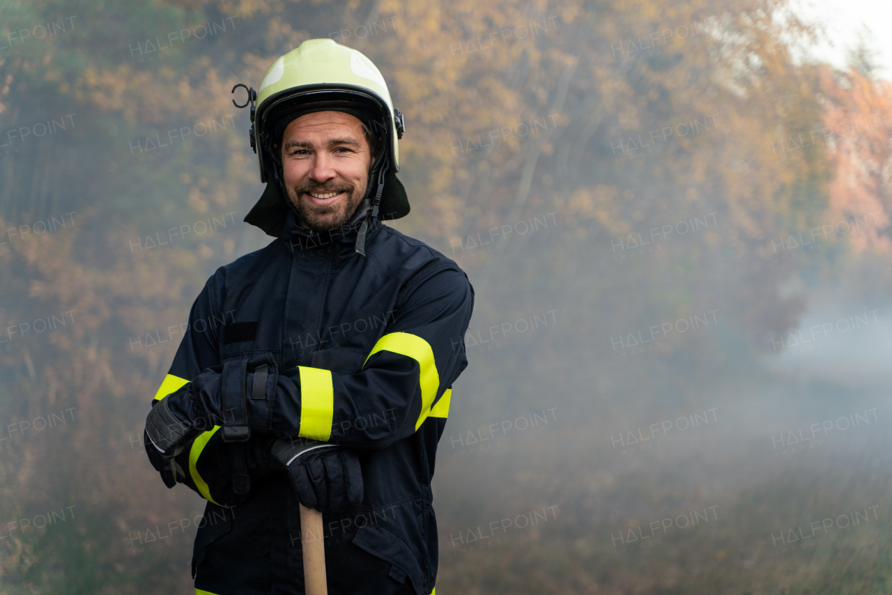 A portrait of happy firefighter man looking at camera after successful action in forest