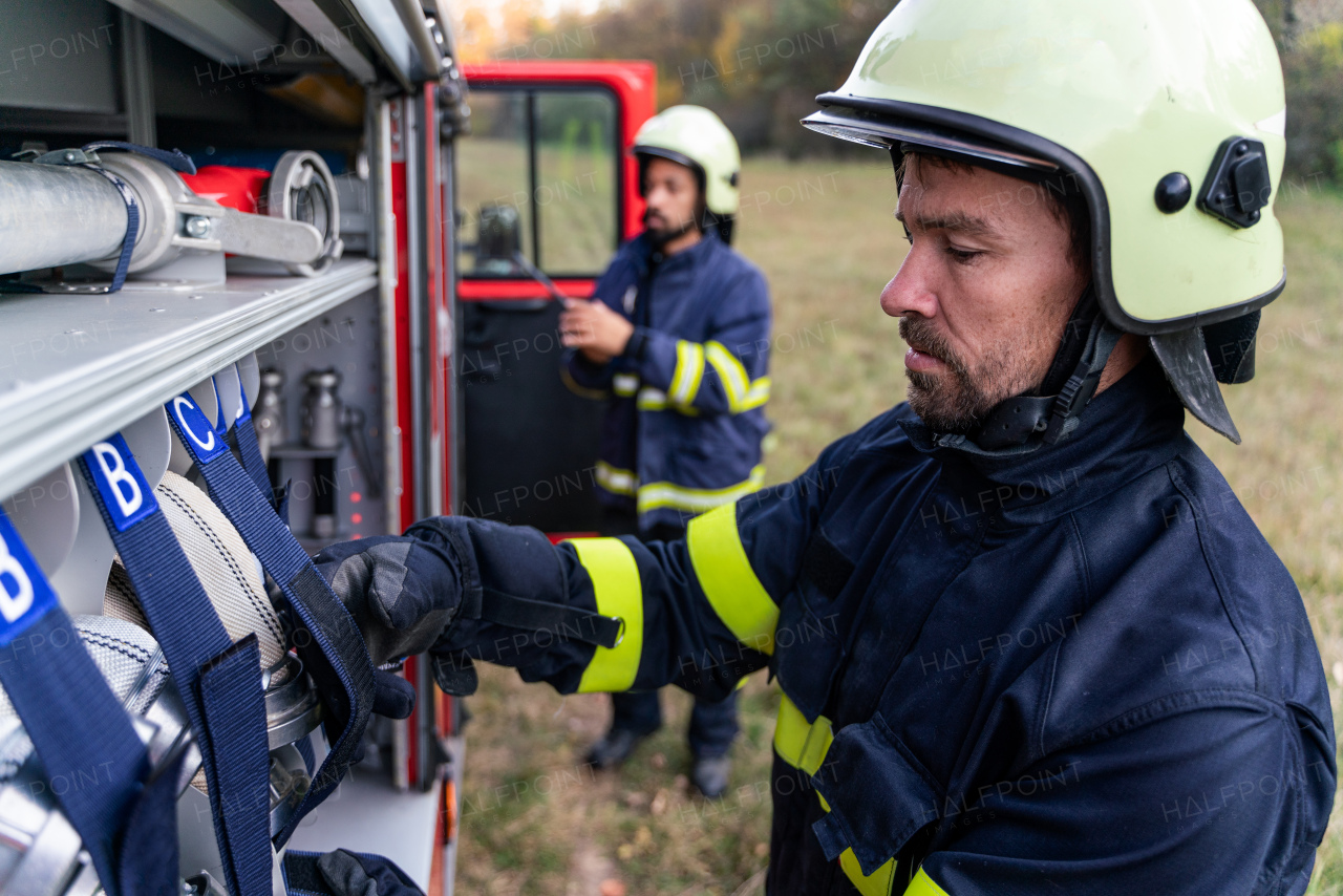 Firefighters men taking an oxygen mask from fire truck outdoors in nature.