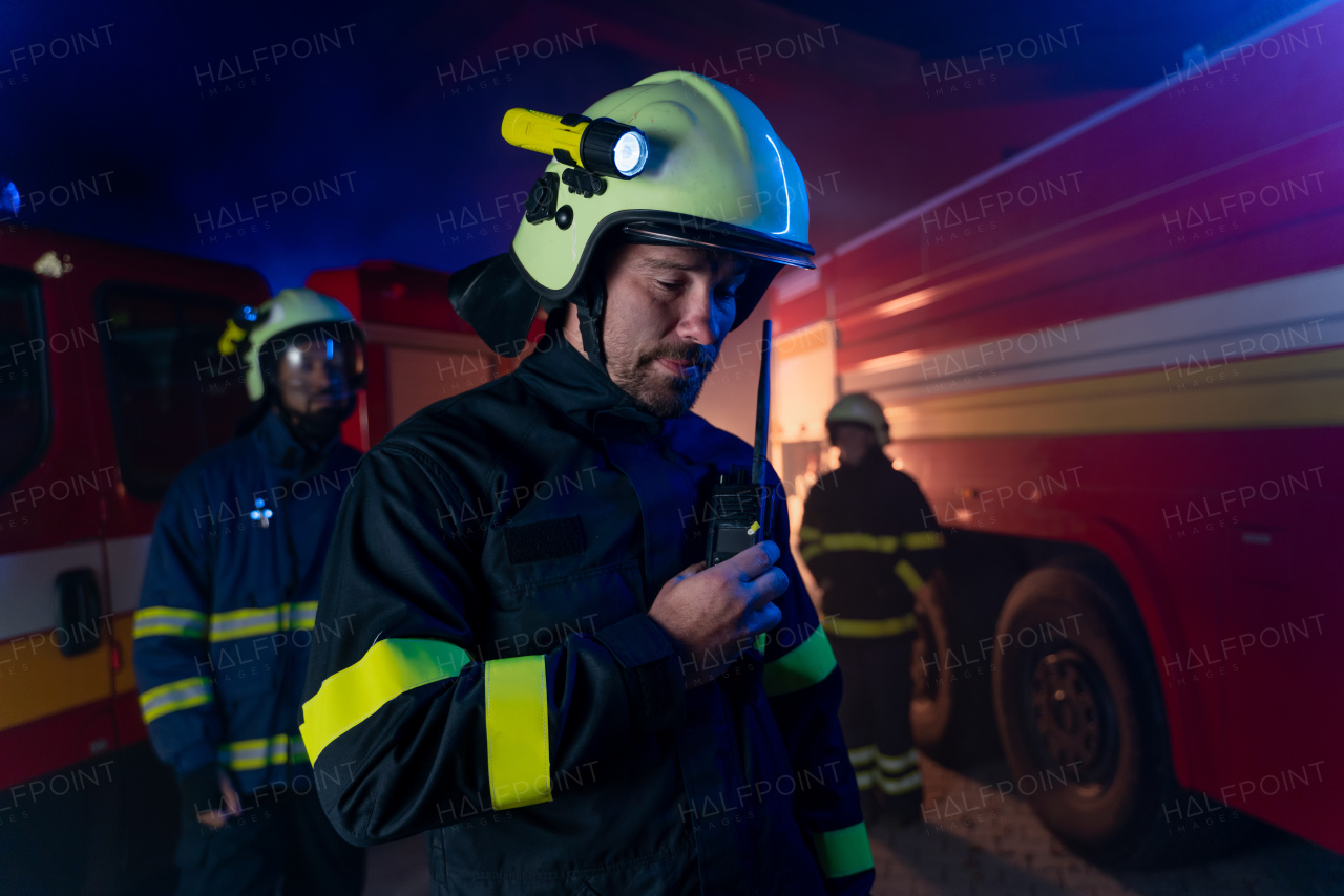 Firefighters men and woman looking at camera with a fire truck in background at night.