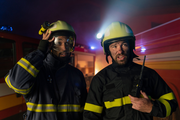 Firefighters men at action with fire truck in background at a night