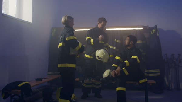 Happy firefighters men and woman after an action celebrating success indoors in fire station